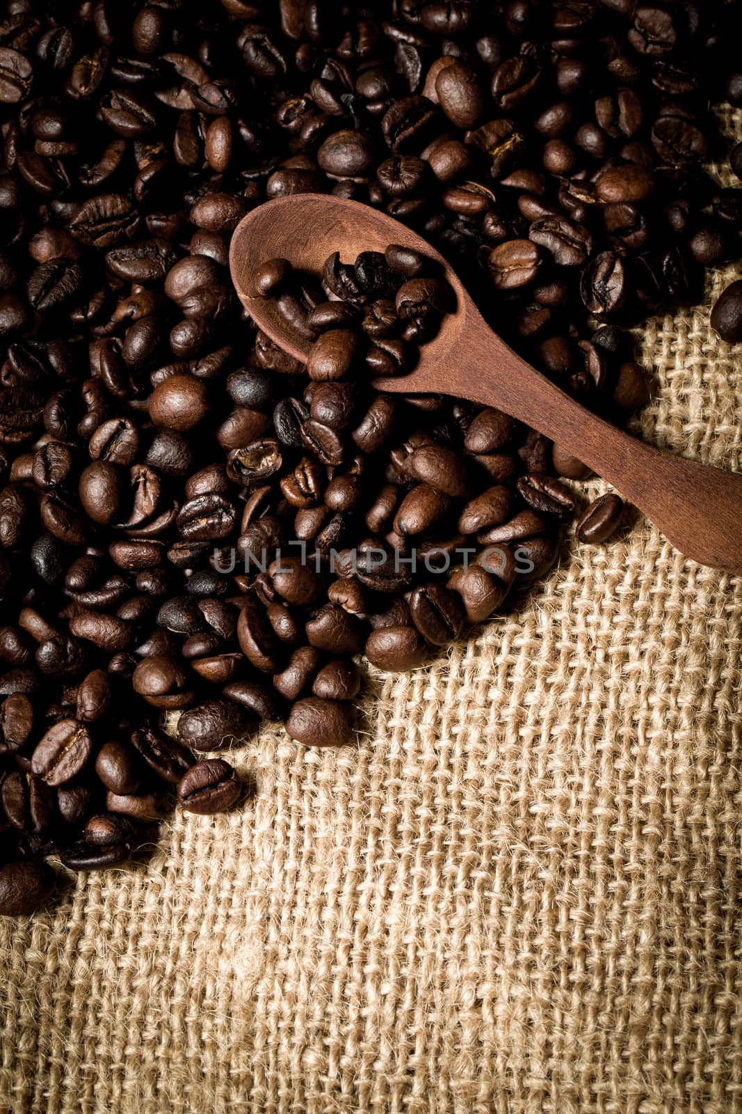 pile of fresh and bio aromatic coffee beans and wooden spoon with space for text