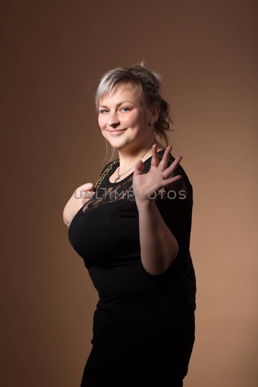 portrait of beautiful smiling plus size young blond woman posing with designer handbags and black dress