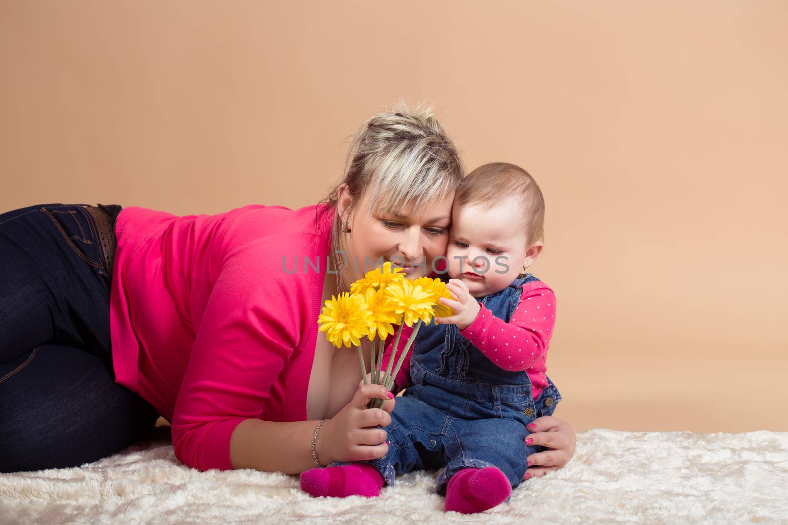 infant baby with his mom and yellow flowers- the first year of the new life