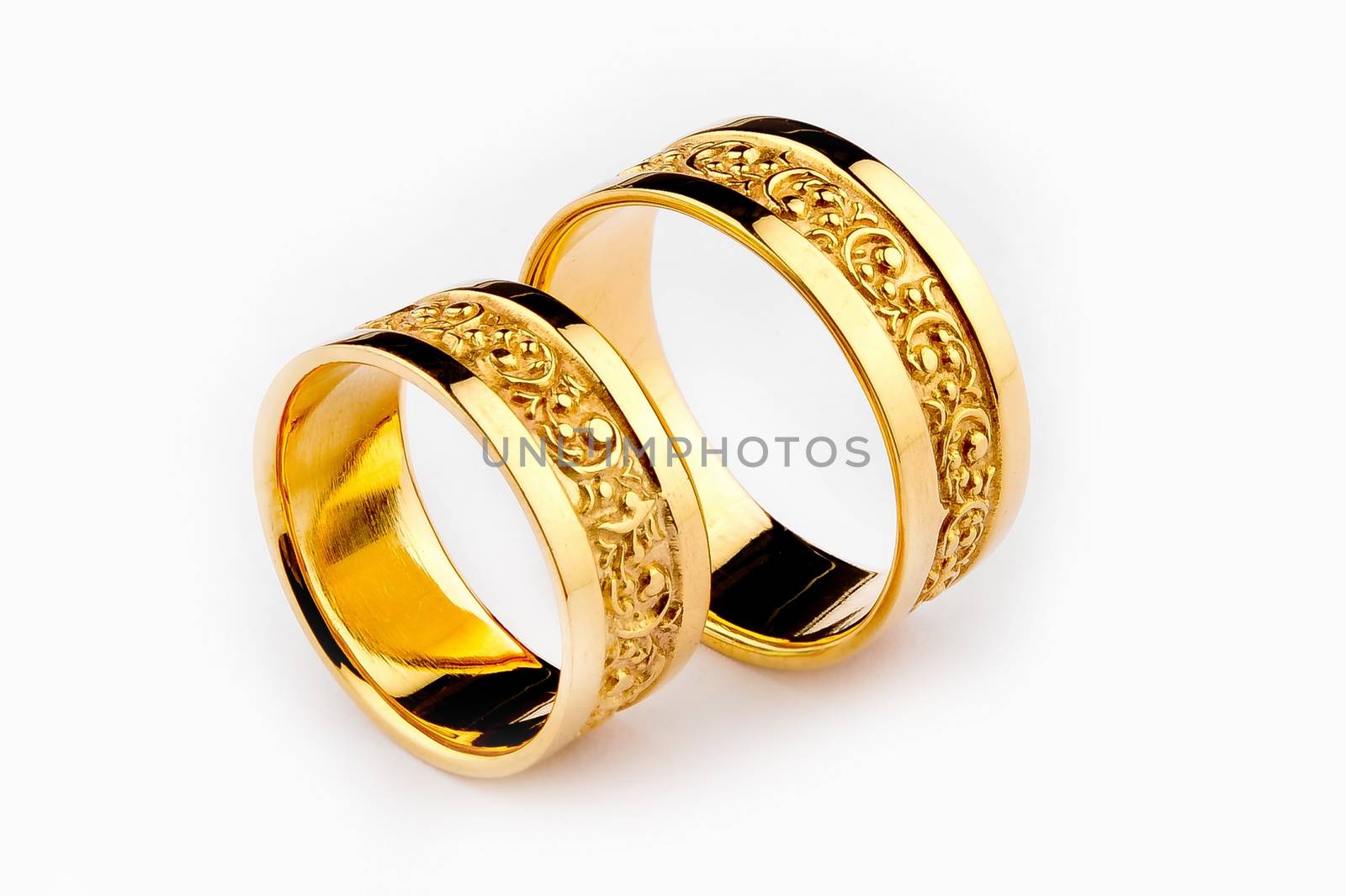 Pair of handcrafted gold wedding rings on white background