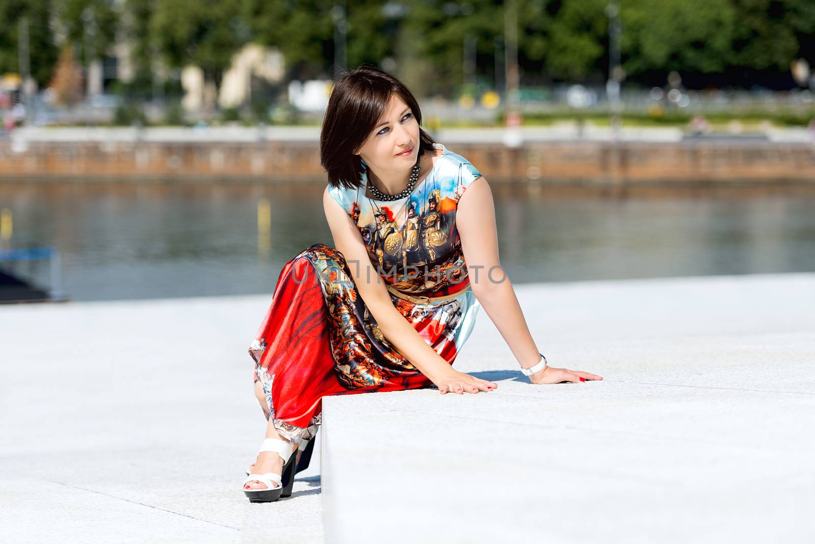 Model in dress posing on exterior set sitting by Nanisimova