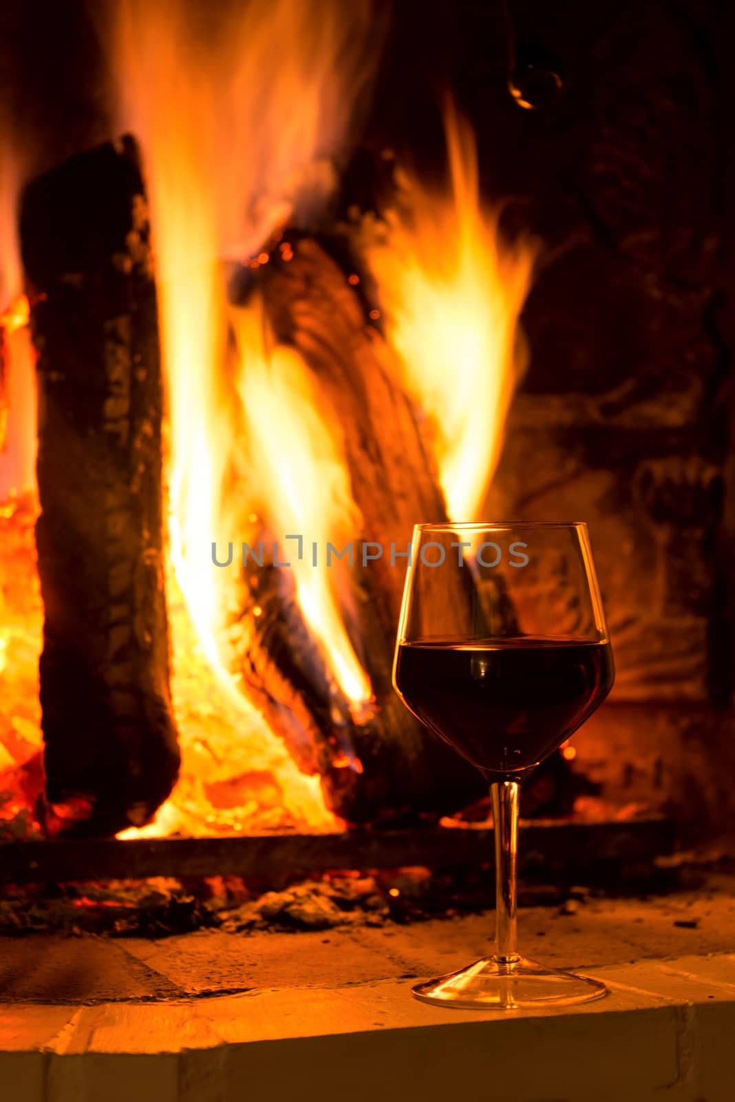 Glass of red vine near fireplace copy space by Nanisimova