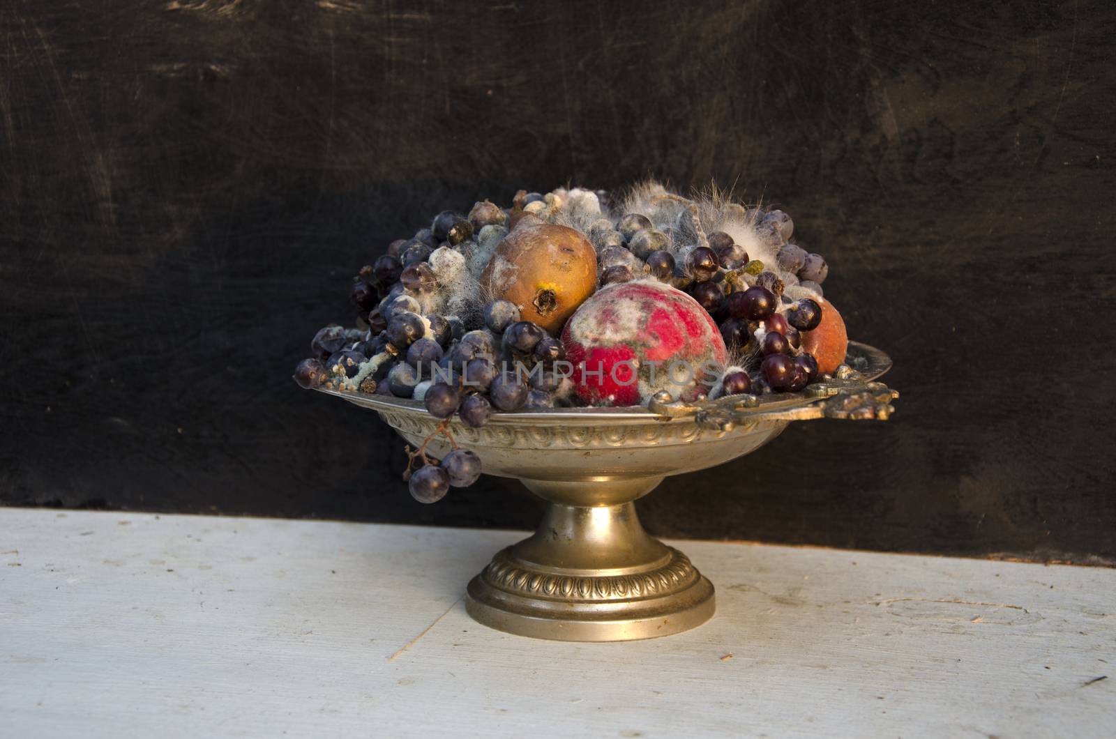 antique pedestal dish vase with various rotten fruits on table