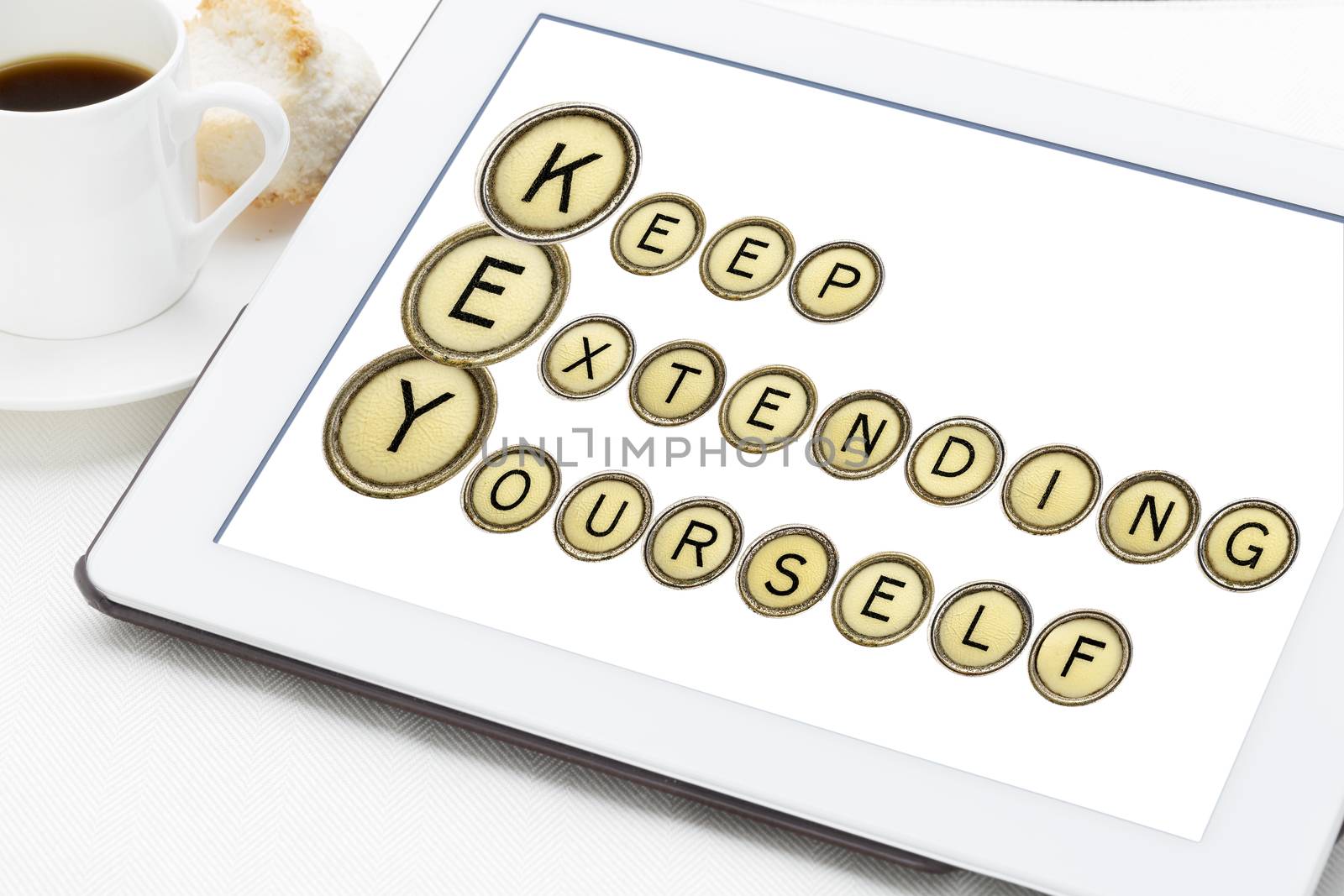 KEY - keep extending yourself - motivation acronym explained in isolated vintage typewriter keys on a digital tablet with a cup of coffee