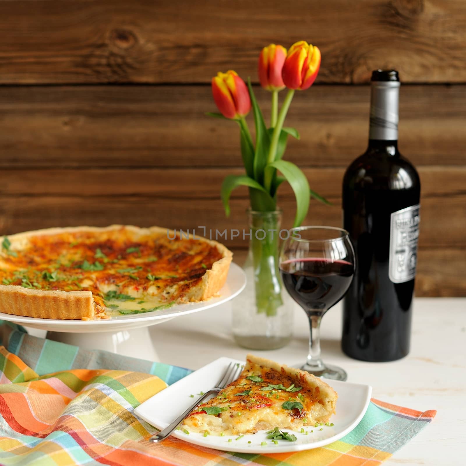 Cheese tart with red wine and red tulips on wooden background square