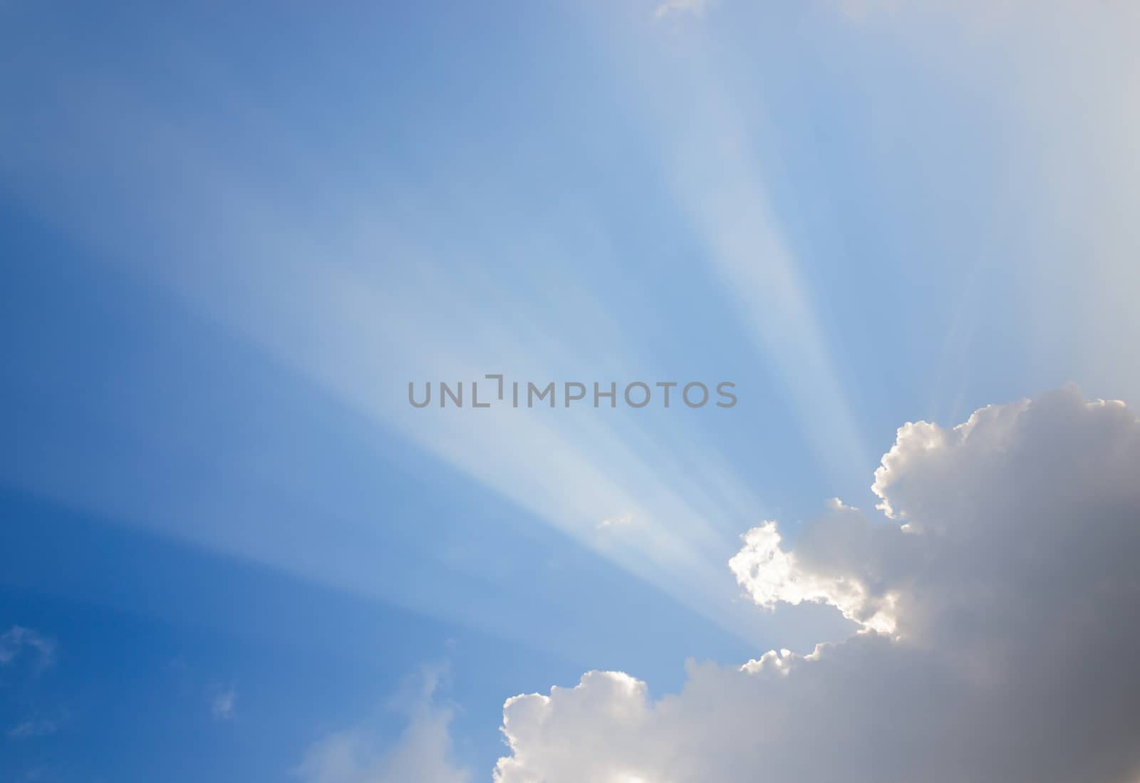 Sunrays passing through clouds and blue sky