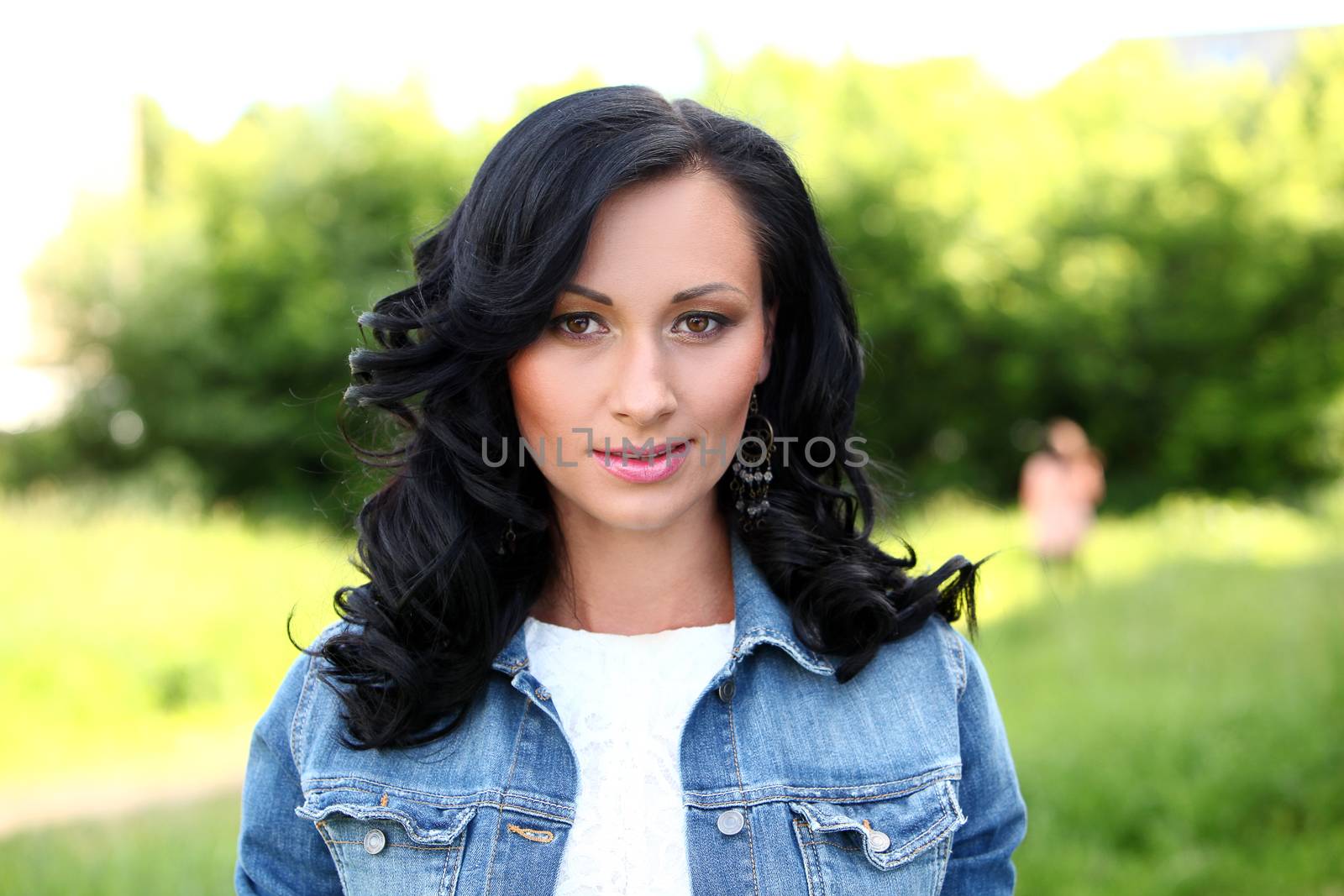 Beautiful brunette woman with curls and makeup in casual at the park