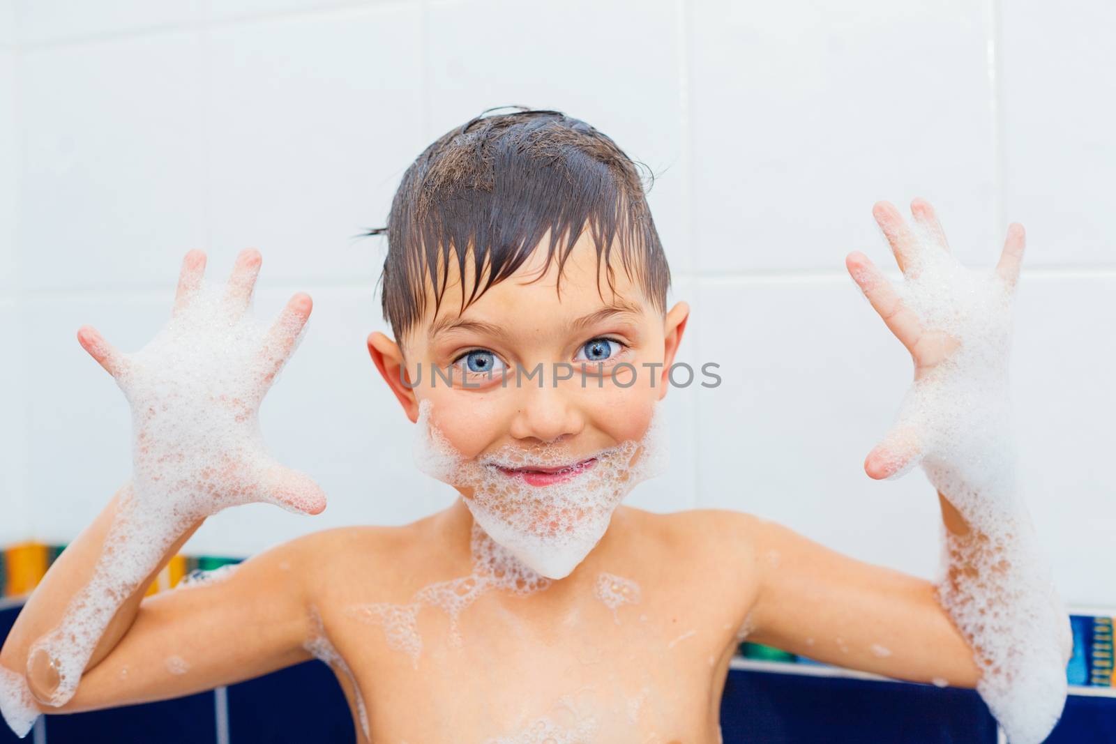 Close-up portrait of cute little boy in bathroom with foam