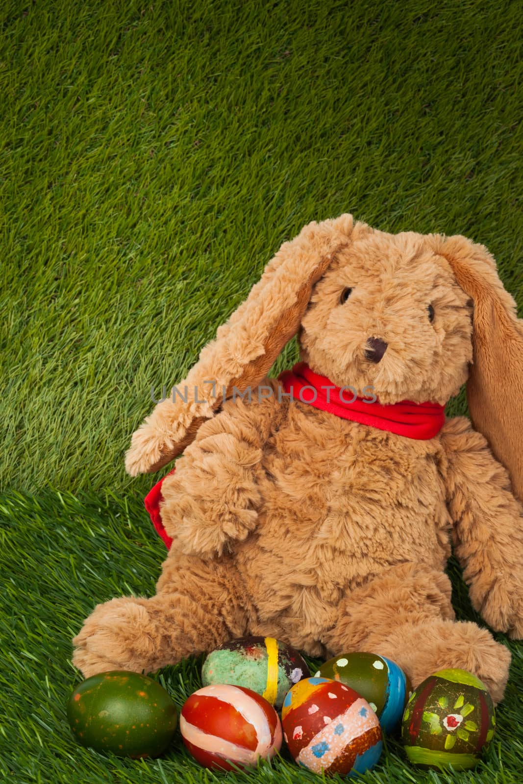 Rabbit, sit on green grass with group of colorful eggs, can use as background for happy easter festival