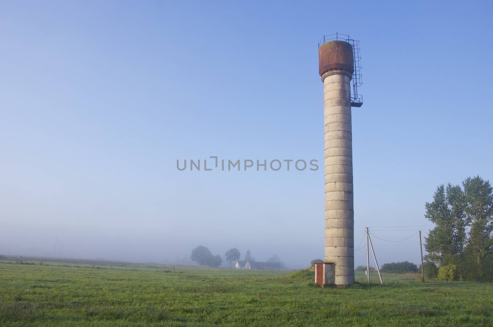 rural early morning landscape with water tower and mist fog