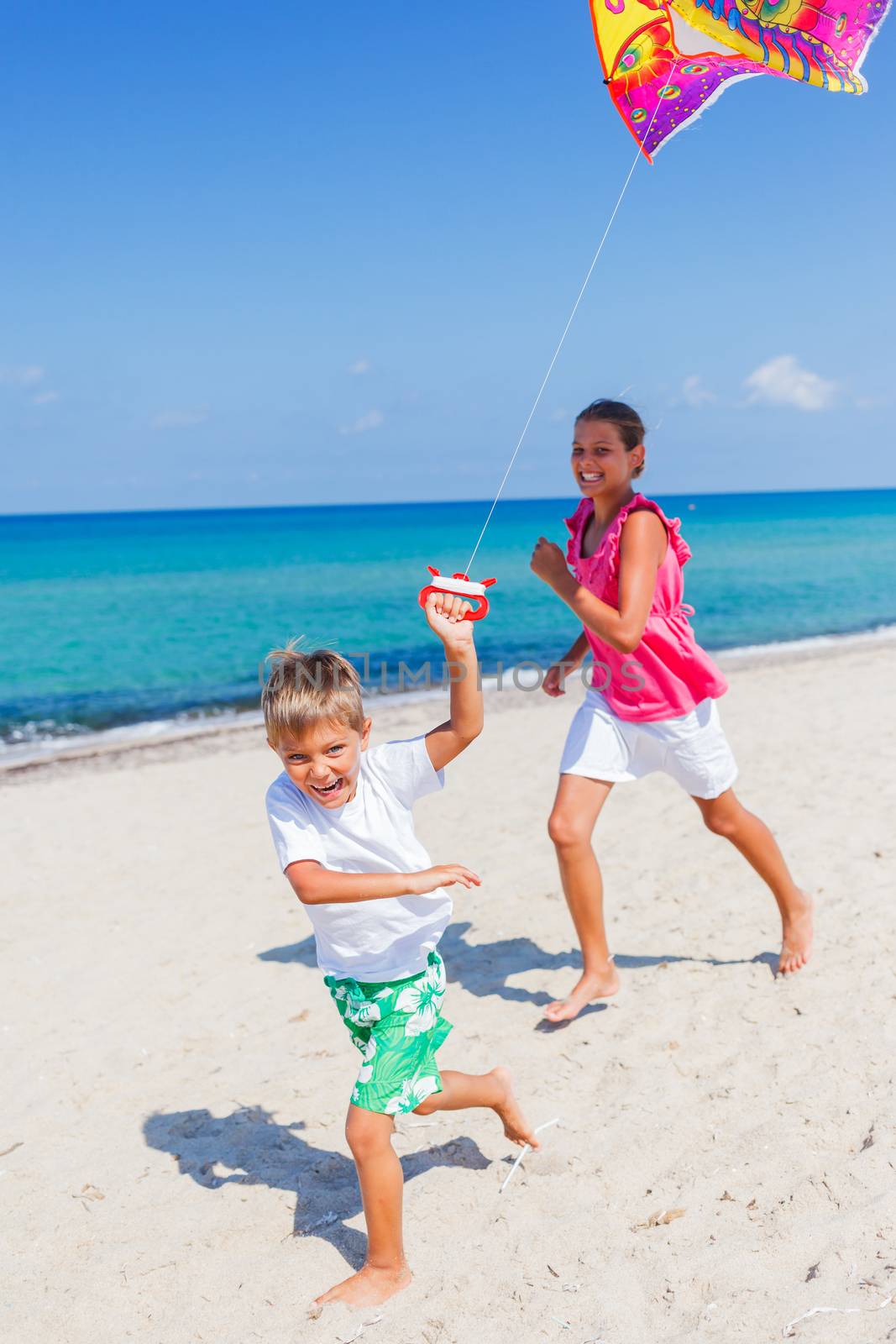 Summer vacation - Cute boy and girl flying kite beach outdoor.