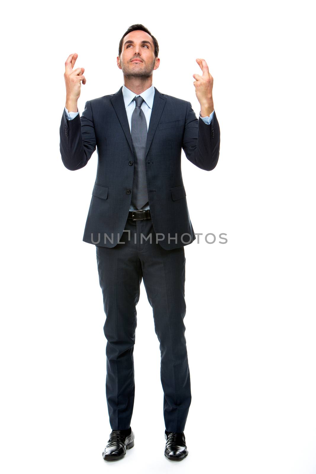 Full length portrait of a businessman looking above and keeping his fingers crossed