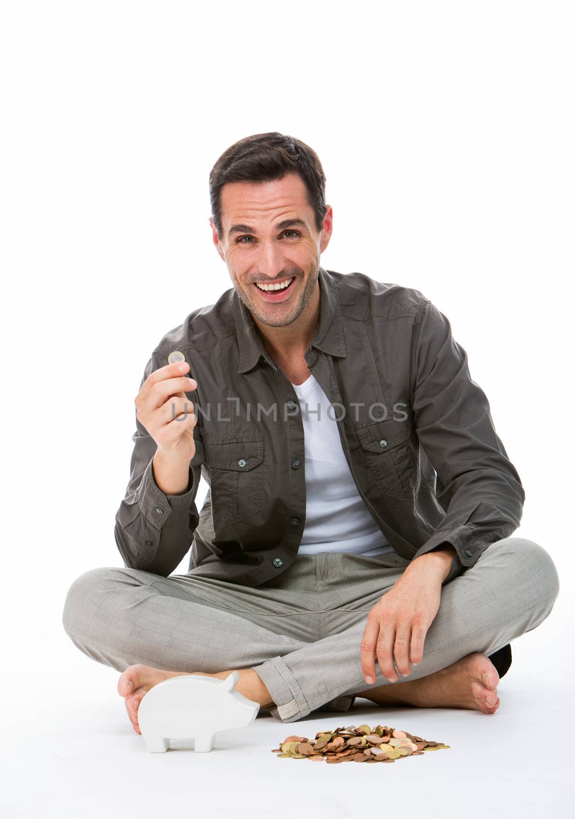 Man seated on the floor, smiling at camera, holding a coin
