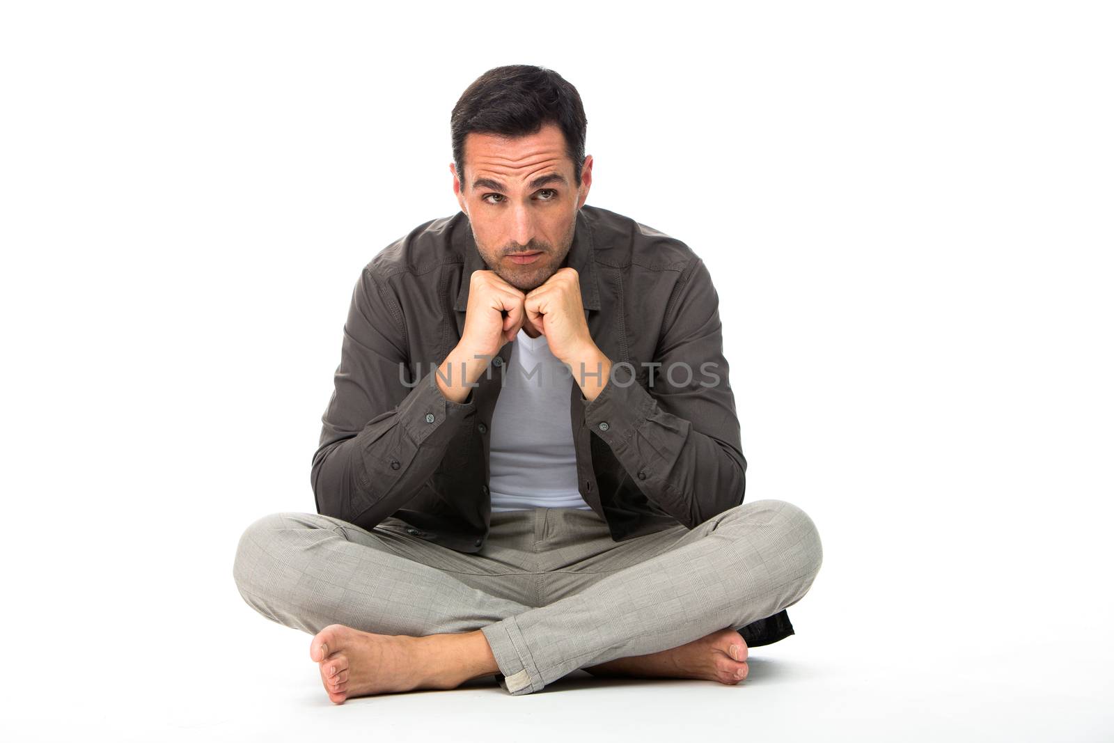 Thoughtful man sitted on the floor with the hands under his chin