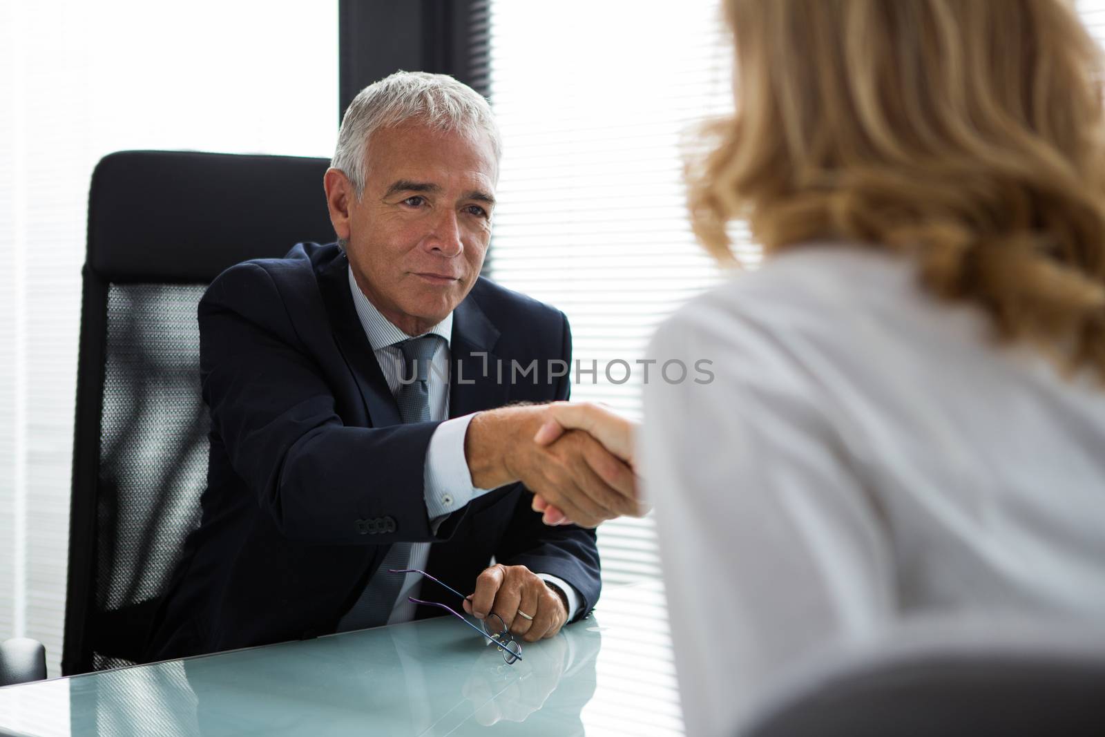 Two businesspeople, male and female, shaking hands during a meeting in the office