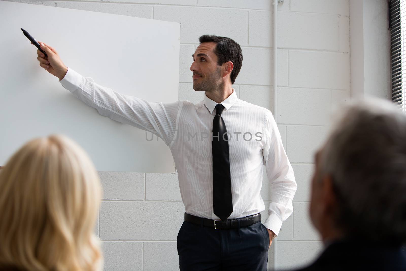 Three businesspeople during a meeting, male manager writing on a blank billboard