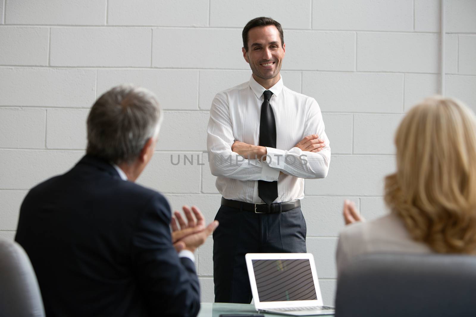 Three businesspeople during a meeting, clapping hands at the end of a presentation