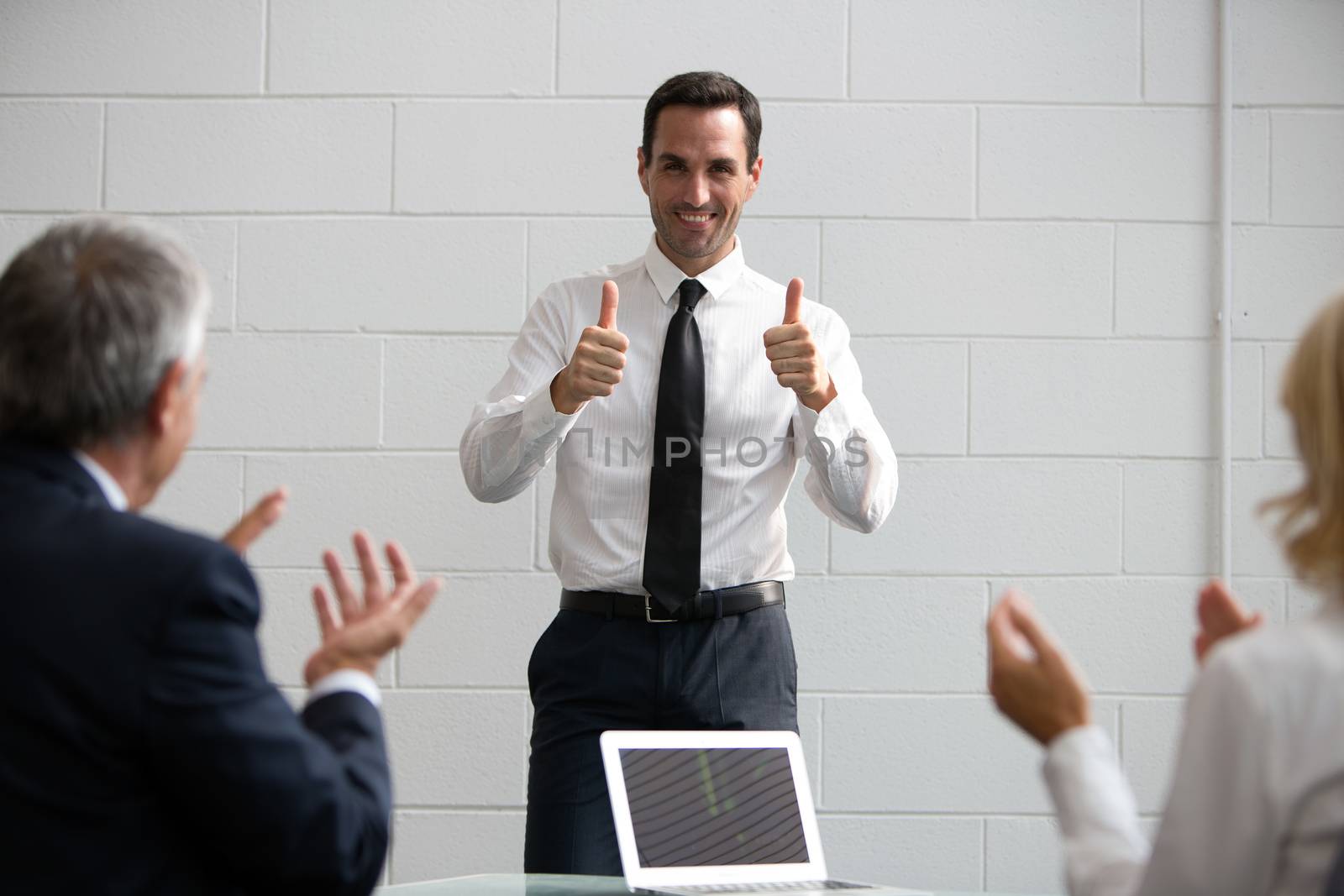 Three businesspeople during a meeting, clapping hands at the end of a successful presentation