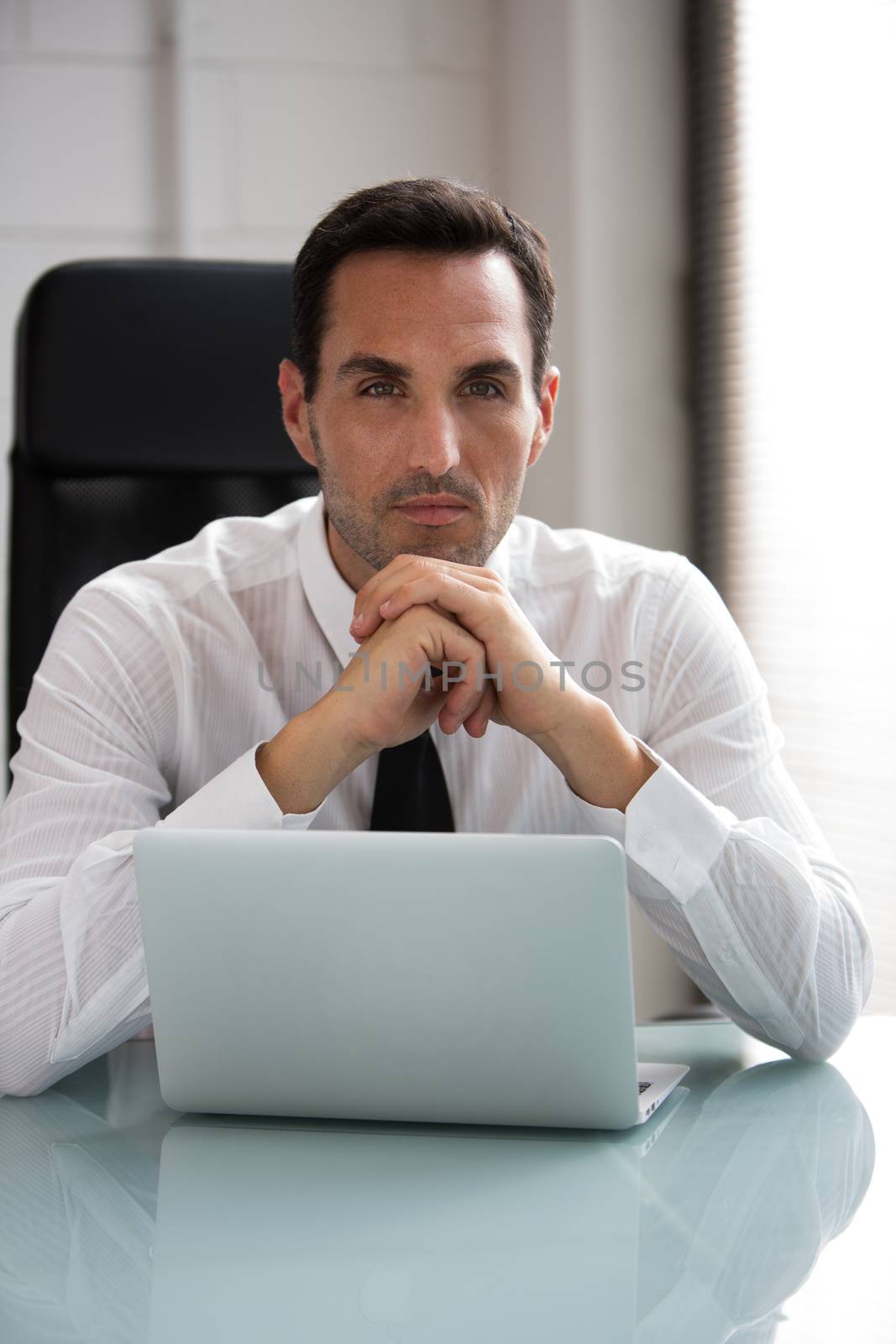 Half length portrait of a thoughtful male businessman working with a laptop computer with hands below his chin
