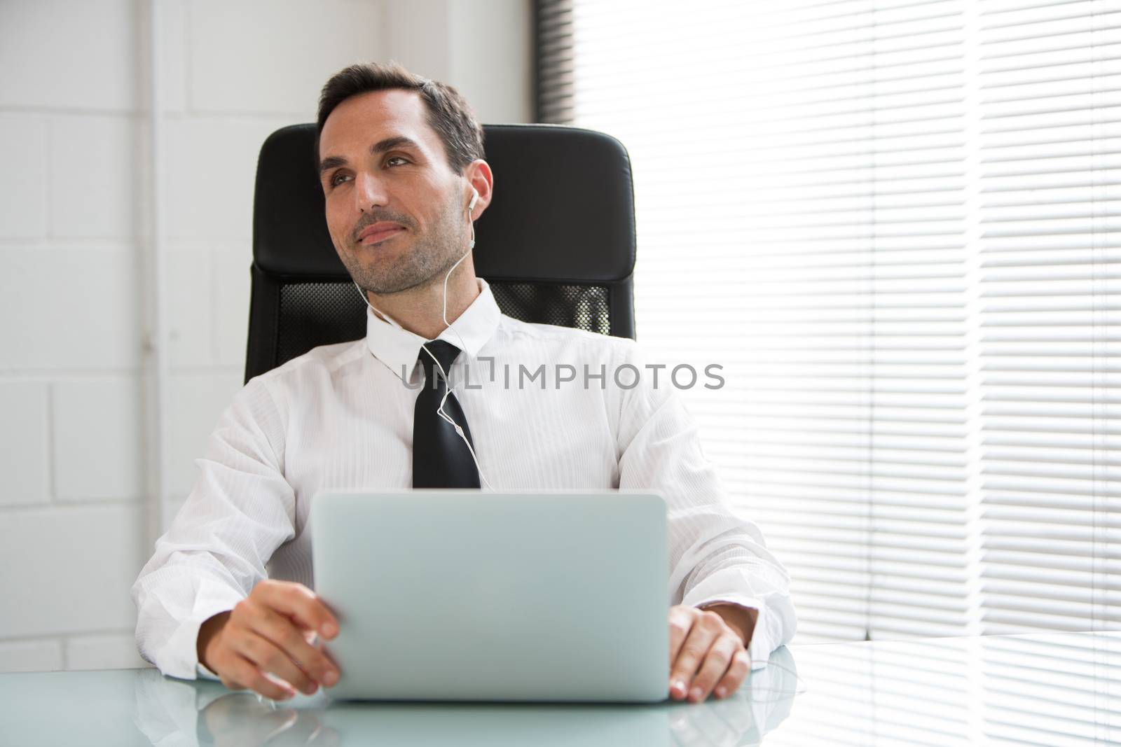 Half length portrait of a male businessman with earphones and laptop computer