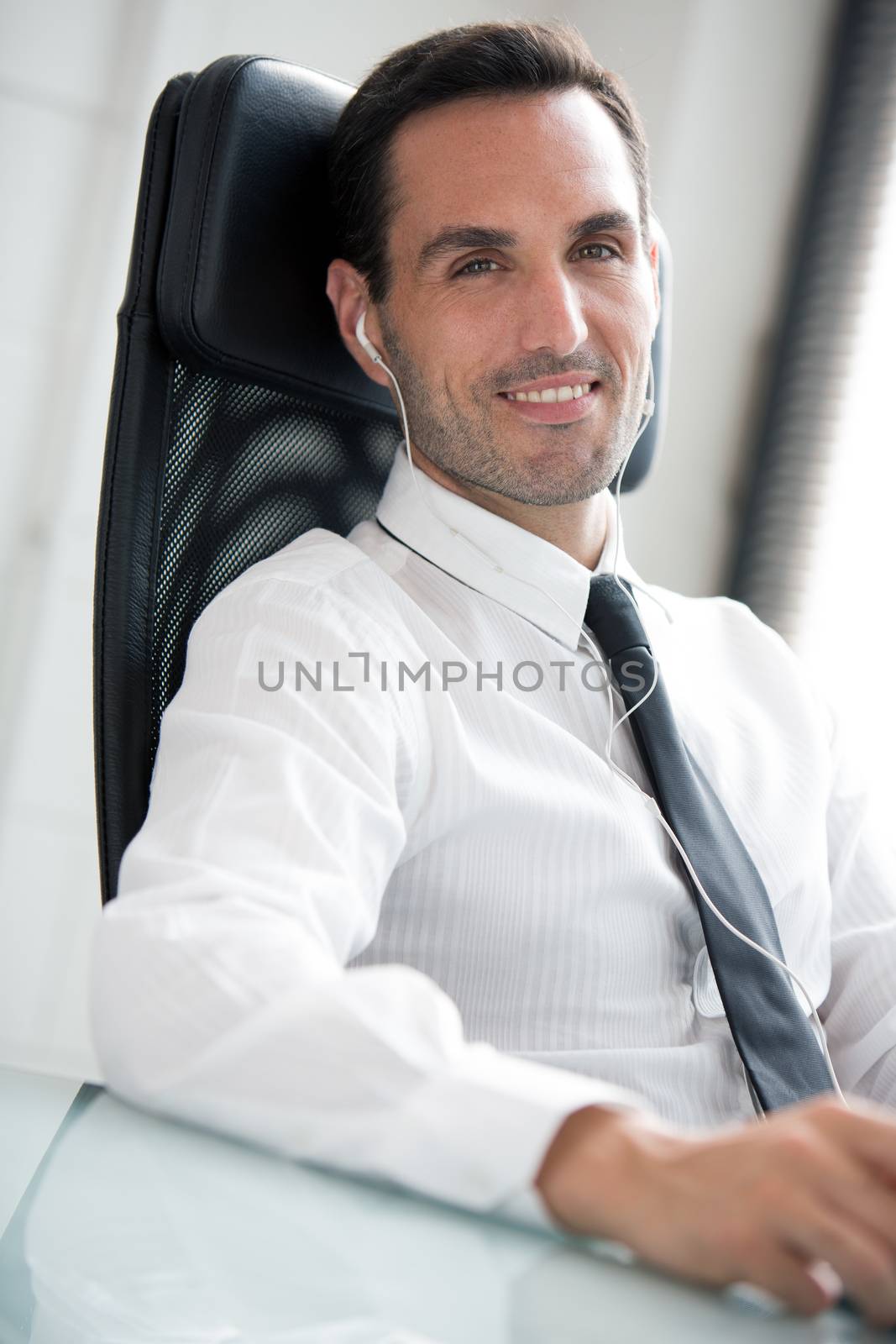 Half length portrait of a male businessman with earphones, smiling at camera