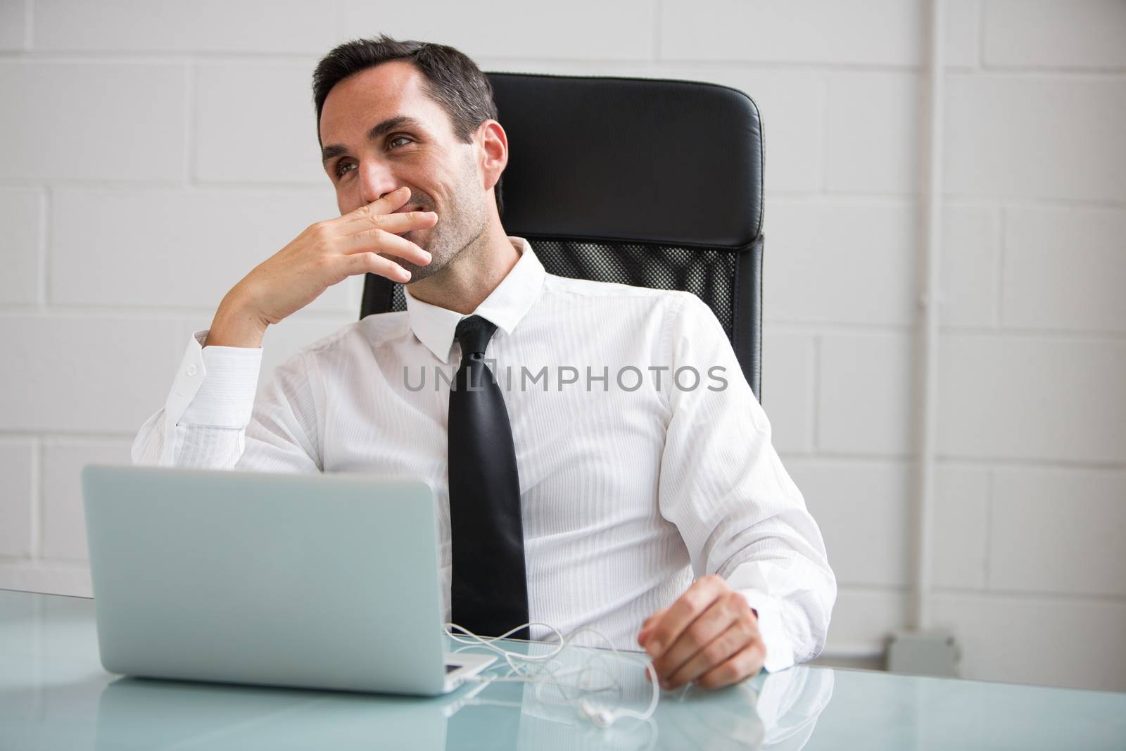 Half length portrait of a male businessman with earphones and laptop computer