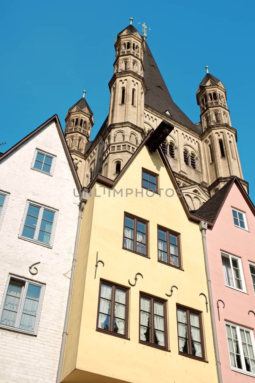 Some ancient colored houses and the tower of Great Saint Martin Church in old town Cologne along river Rhine