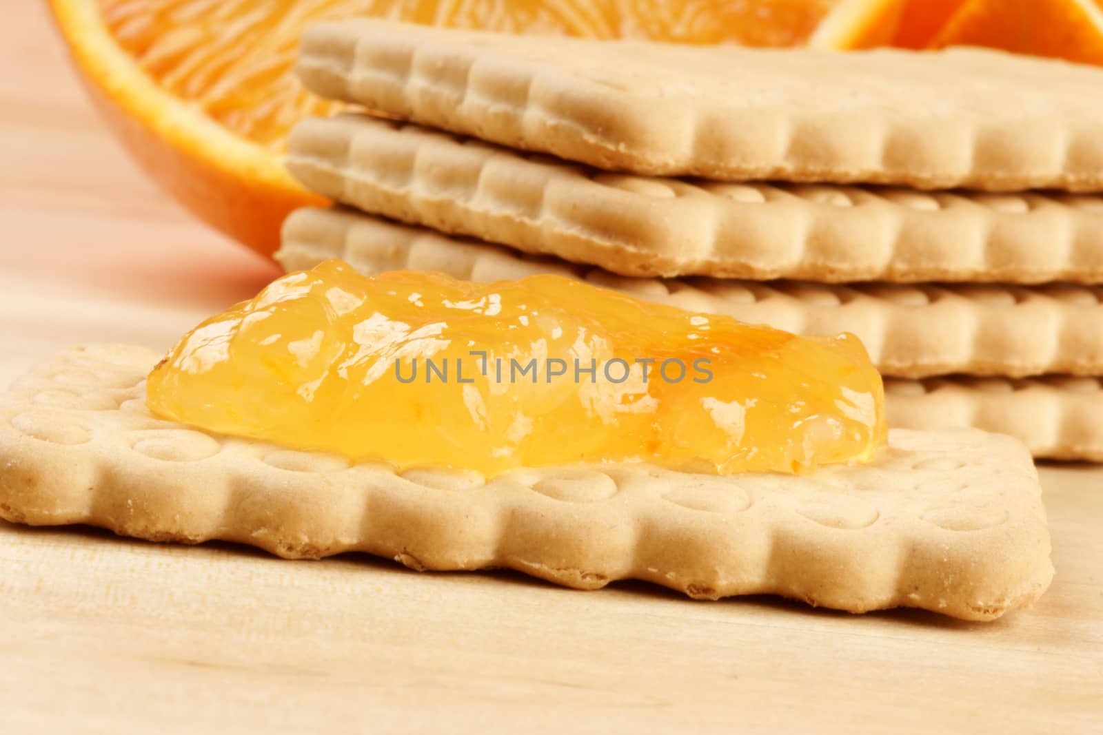 Macro of a biscuit with marmalade. In the background some other biscuits and oranges.