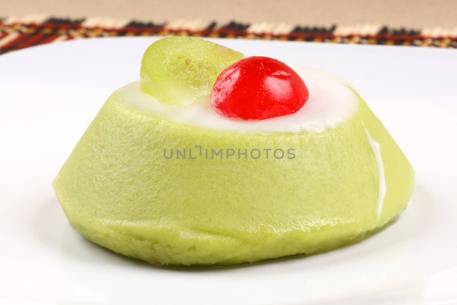 Close-up of a mini sicilian cassata with pieces of candied fruit served on a white dish