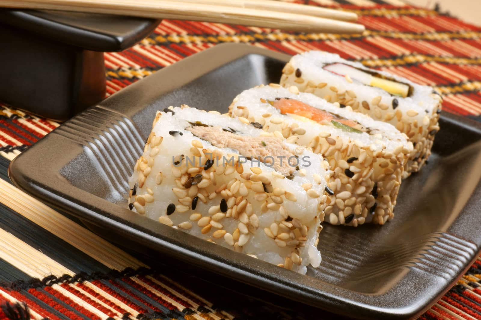 Assorted japanese maki sushi on a black tray with chopsticks, ready to be eaten, Selective focus