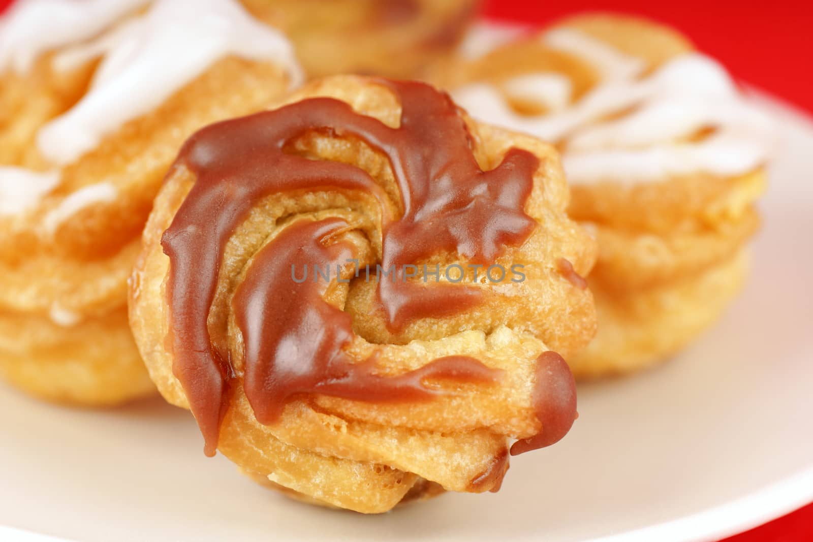 Zeppole di San Giuseppe or St. Joseph's Day Cream Puffs, are south italian deep fried cakes, filled with custard and frosted. Isolated on red.
