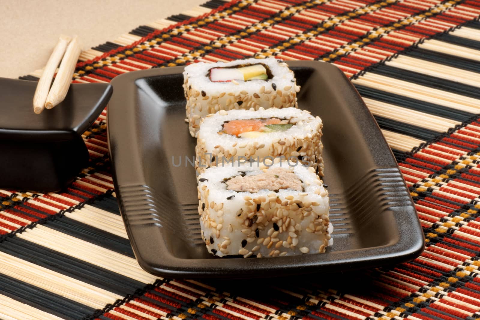 Assorted japanese maki sushi on a black tray with chopsticks, ready to be eaten. Selective focus.