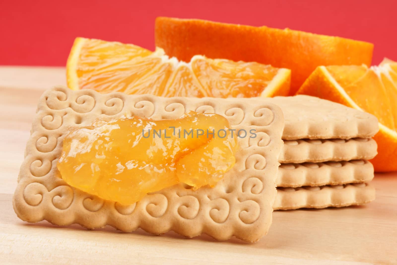 Biscuits, marmalade and slices of orange on a wooden cutting board