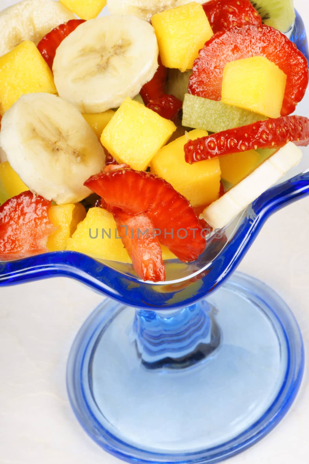 Close-up of a colorful fresh fruit salad in a blue glass cup. Selective focus.