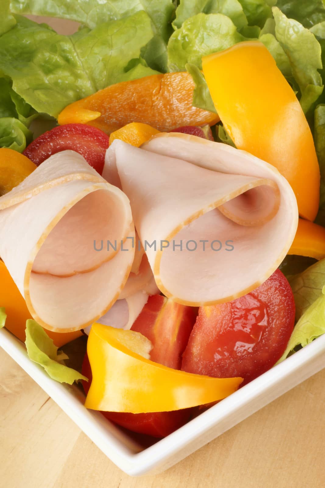 Close-up of a mixed salad with lettuce, tomatoes, bell peppers and roast turkey