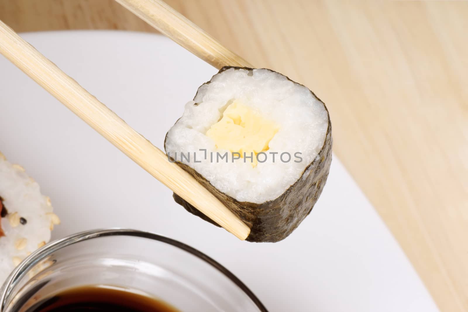 Eating maki sushi roll with wooden chopsticks. Selective focus.