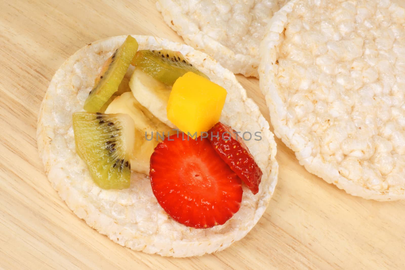 Rice cakes with fresh fruit slices, over a wooden background