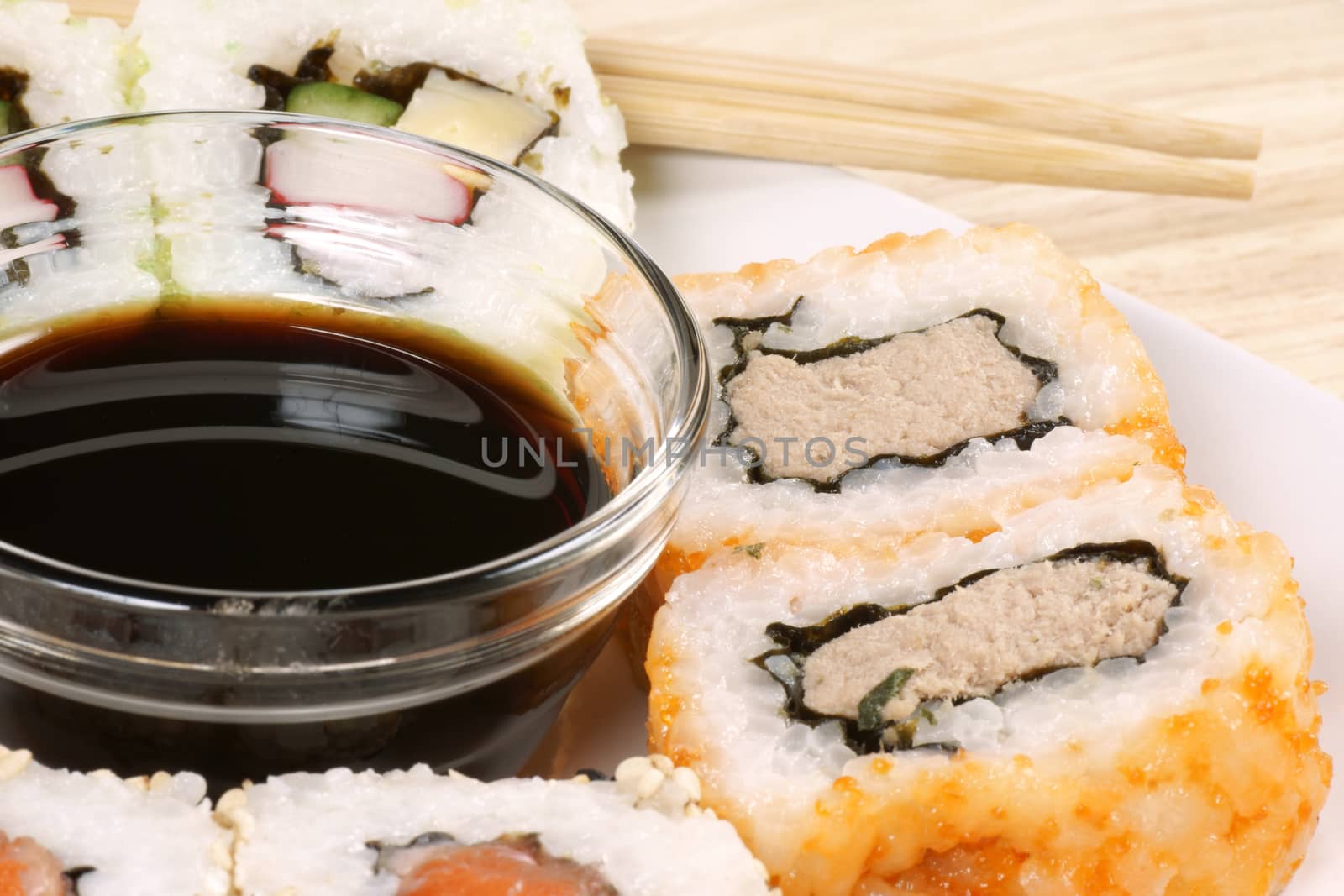 Close-up of Maki sushi rolls served on a plate with soy sauce and chopstick on a wooden table