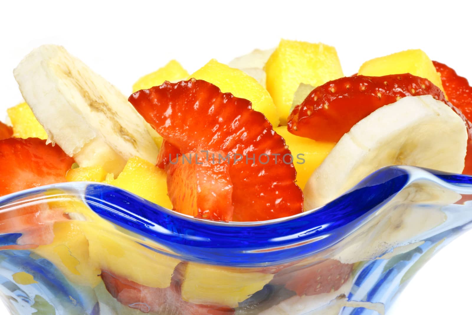 Close-up of a colorful fresh fruit salad in a blue glass cup.