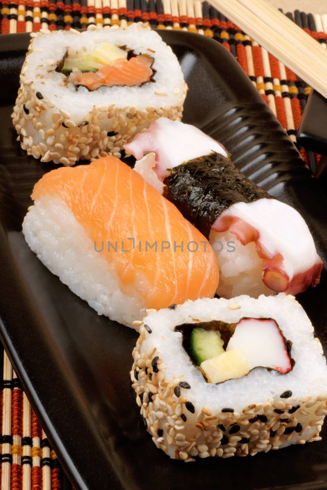 Assorted sushi served on a black plate with wooden chopsticks