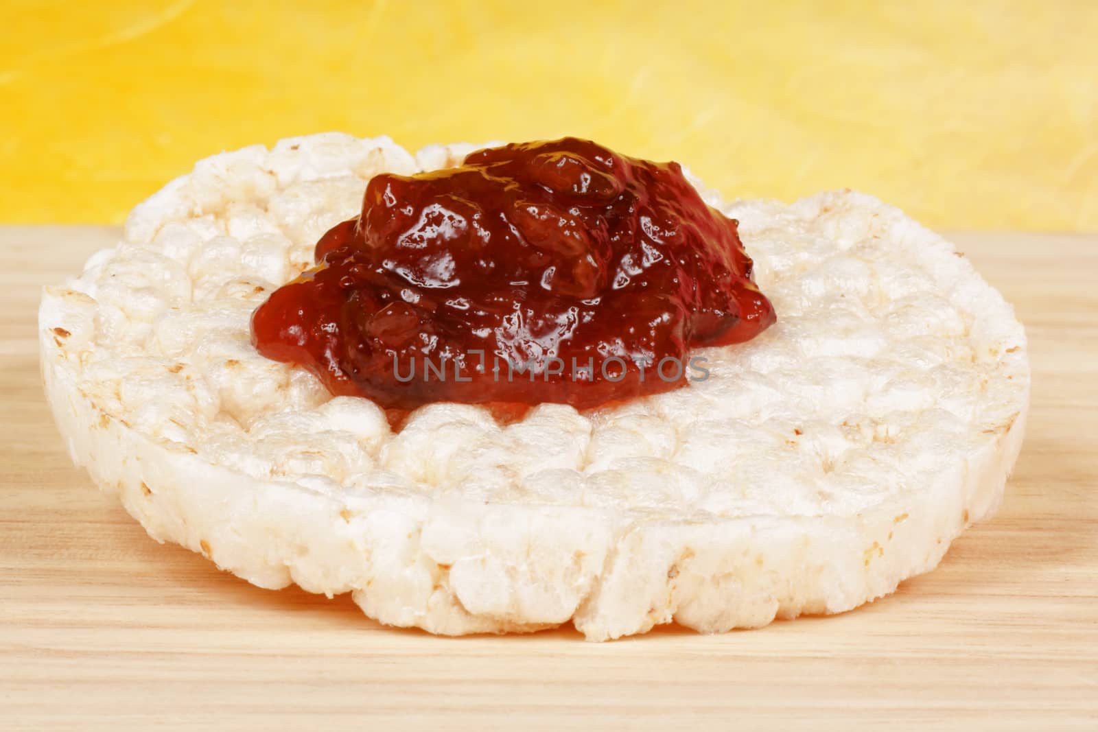 Close-up of a rice cake with jam on a wooden background for an healthy breakfast. Selective focus.