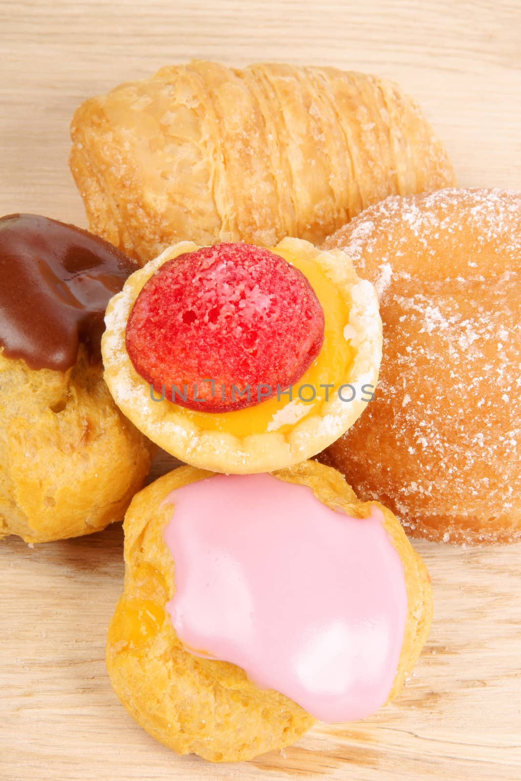 Assorted tea cakes on a wooden cutting board over a green background.