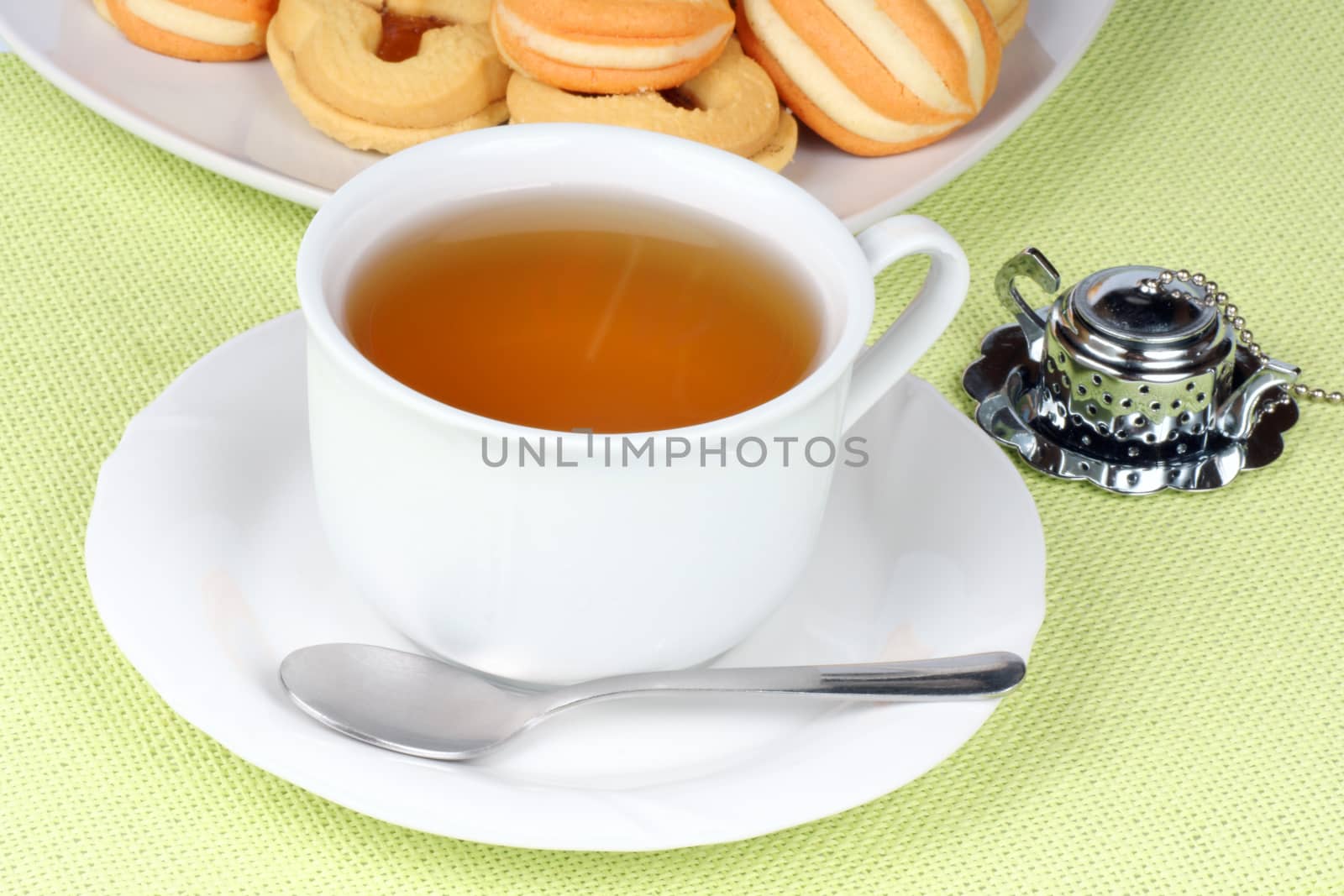 Close-up of a cup of tea and some shortcrust pastry biscuits over a light green background