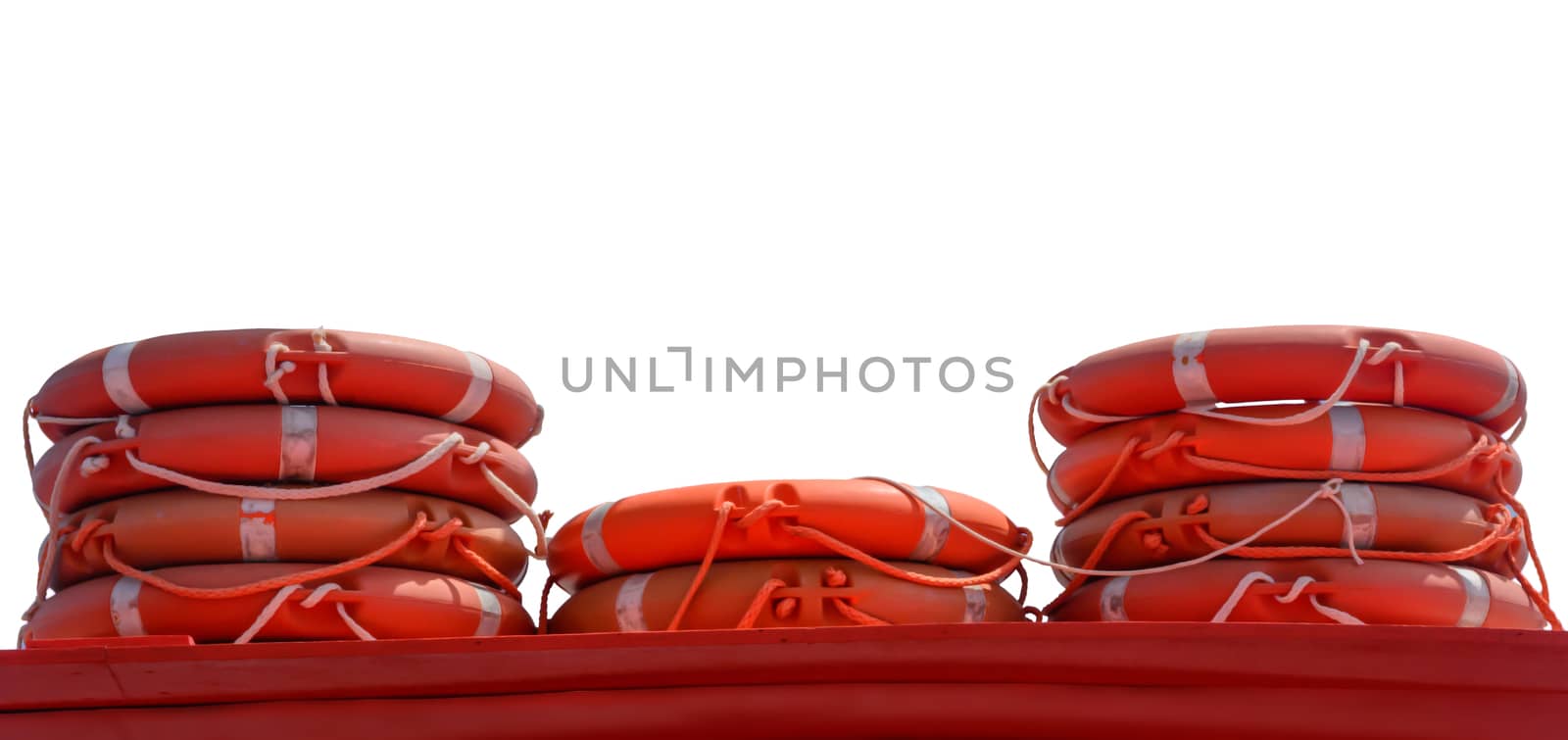 Life rings in orange color stacked on a boat with blue sky, ad space.