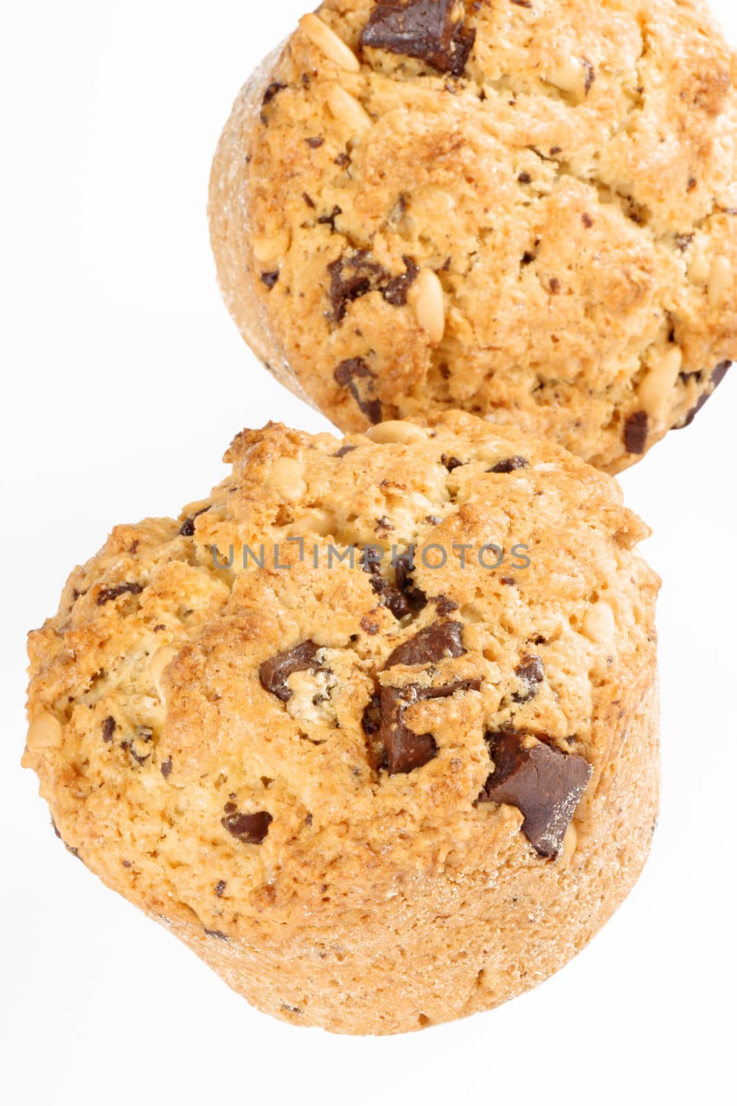Freshly baked chocolate chip and pine nut muffin over a white background