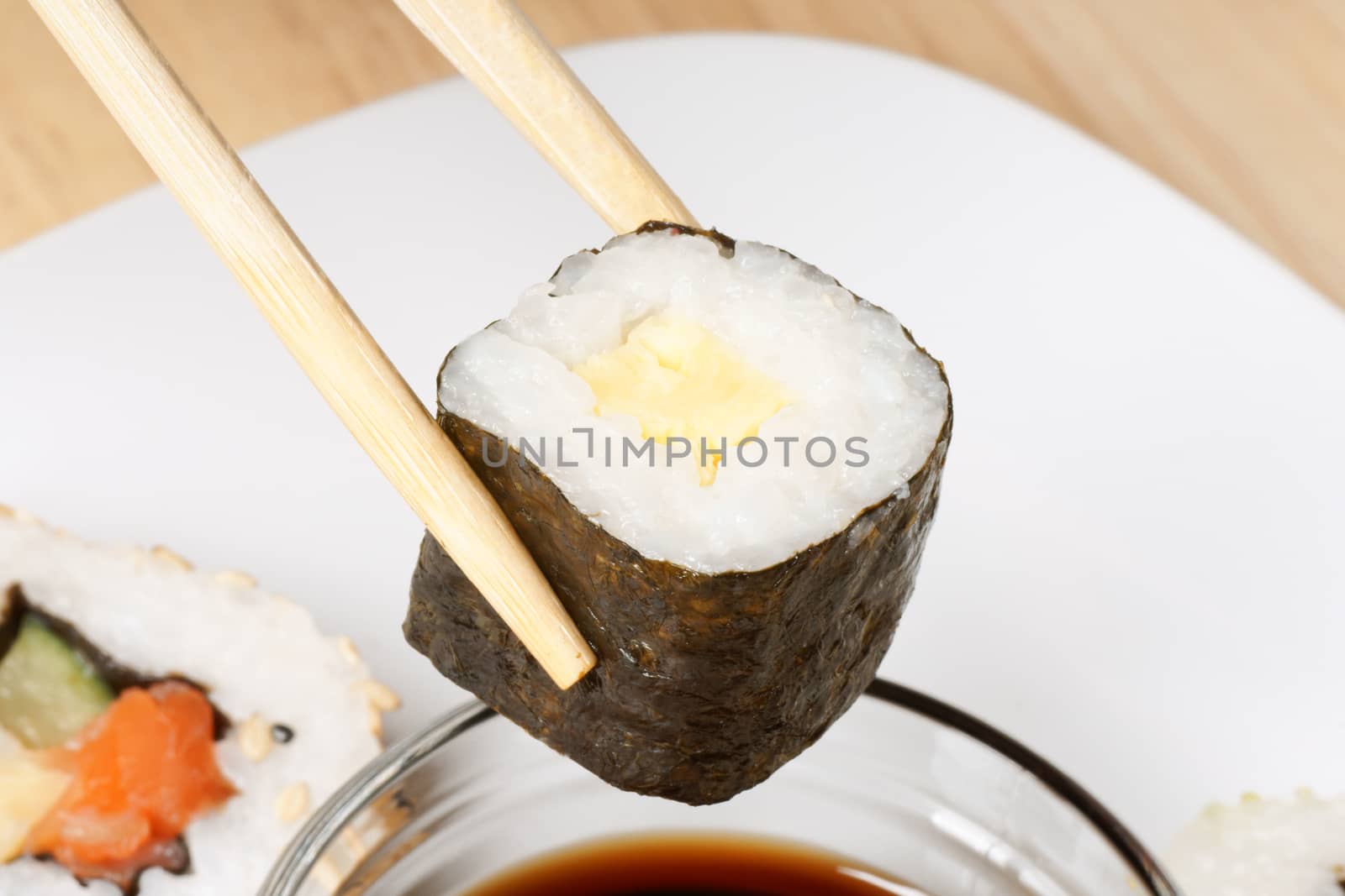 Eating maki sushi roll with wooden chopsticks. Selective focus.