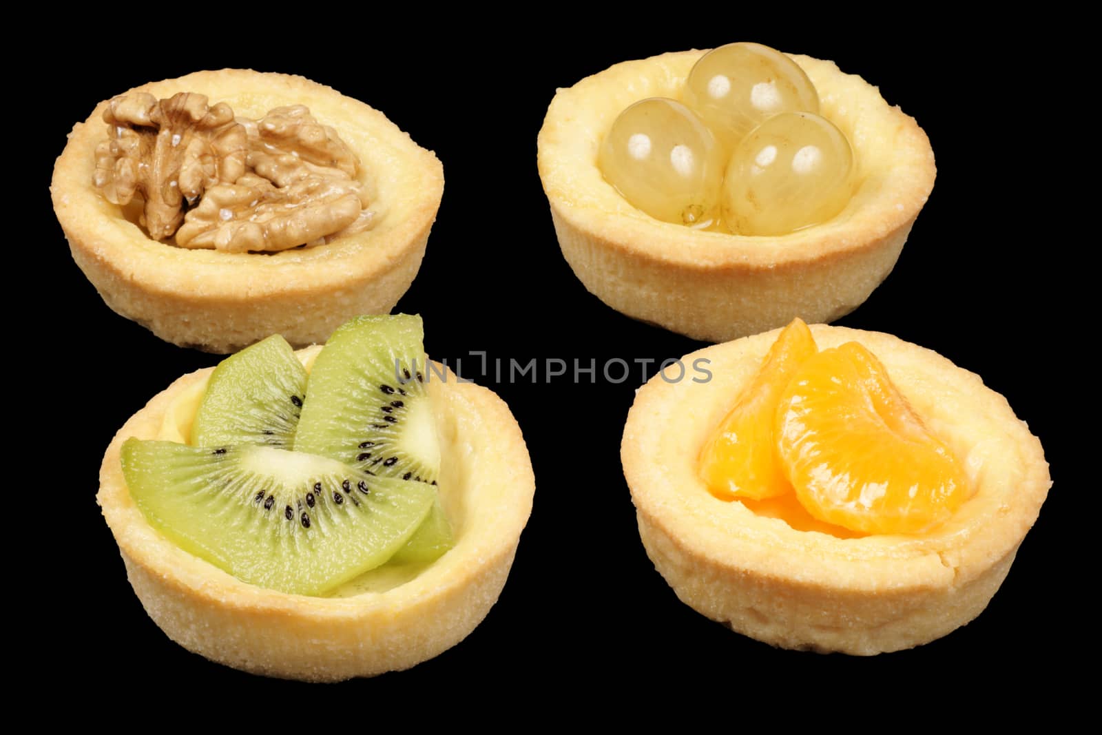 Close-up of four mini fruit tarts over black background