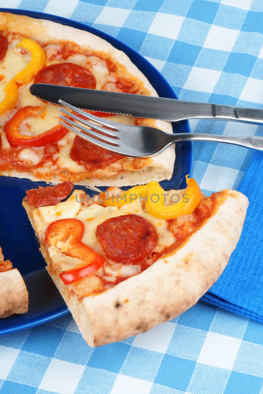 Set table with hot spicy pizza with salami and bell peppers.
