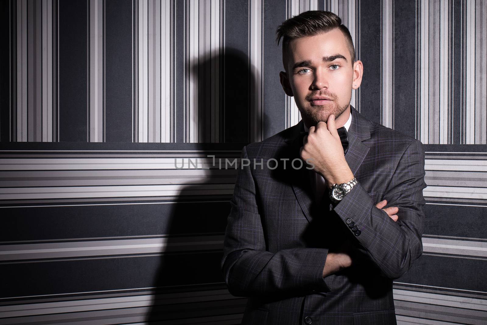 Portrait of a handsome man in a suit and a tie who is posing over a striped background