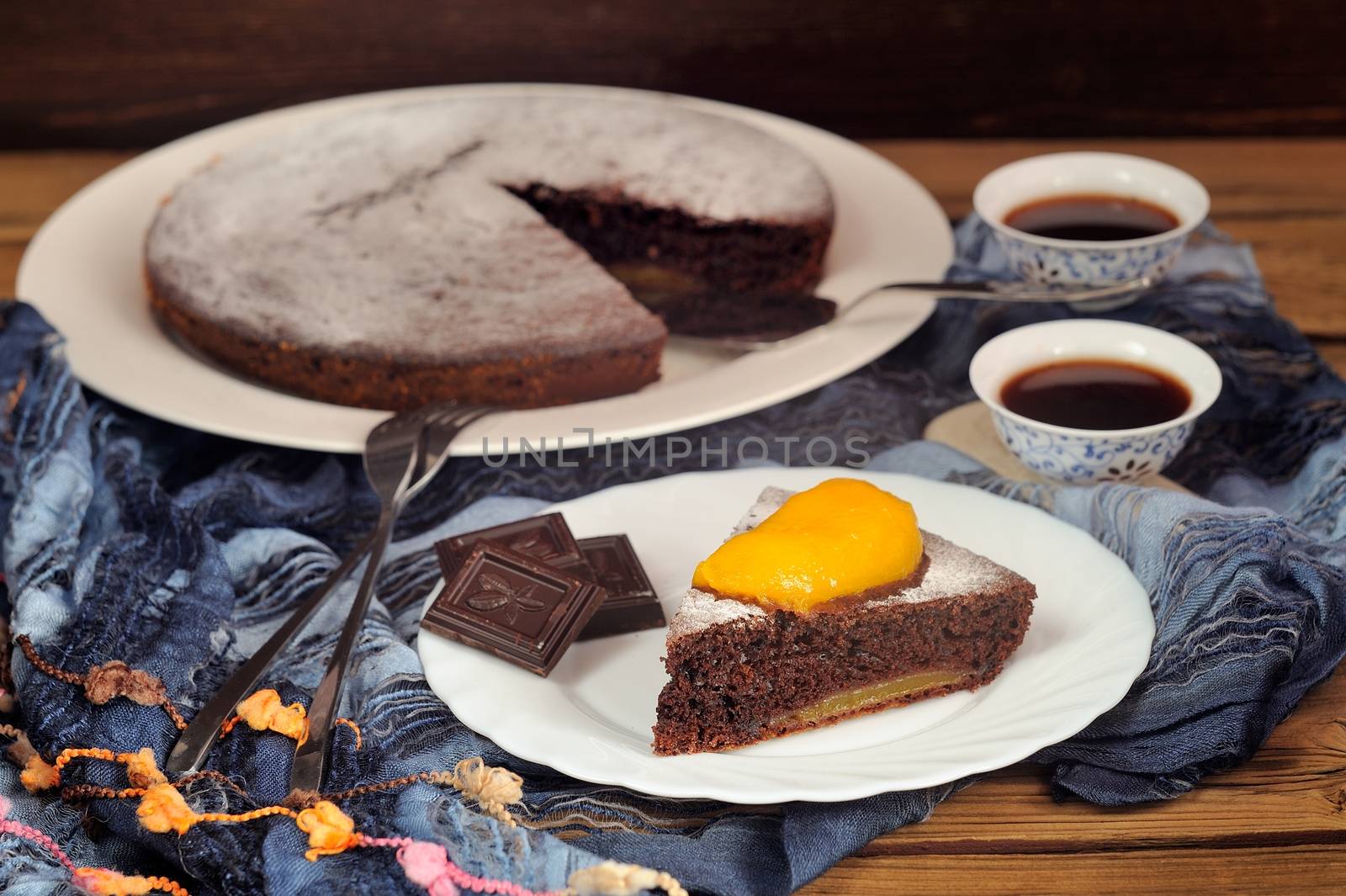 Chocolate cake with mango and black tea on blue cloth horizontal